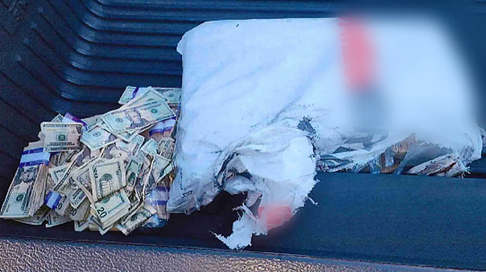 A torn currency bag and loose bundles of banknotes recovered onto the bed of the escort vehicle